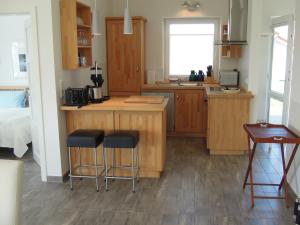 a kitchen with wooden cabinets and bar stools at Schilfuferhaus in Hestoft