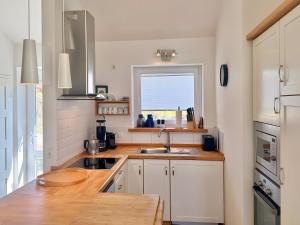 a kitchen with white cabinets and a sink and a window at Rosenuferhaus in Hestoft