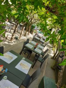 a green table and chairs sitting under some trees at My Home Hotel in Bellaria-Igea Marina
