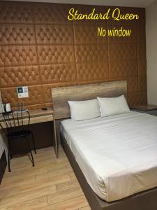 a bedroom with a bed and a desk with a sign on the wall at SH Hotel Kota Damansara in Kota Damansara