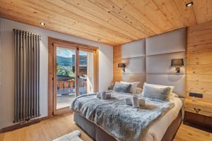 a bedroom with a large bed and a large window at Chalet Ysalpe - Vue montagne hammam sauna jacuzzi et salle cinéma in Megève +31 photos