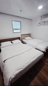 a bedroom with two beds and a window on the wall at 부산해운대바다품 in Busan