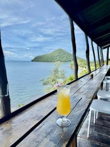 a glass of orange juice sitting on a table overlooking the ocean at On the Rocks in Koh Rong Sanloem