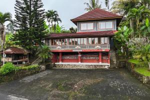 a house with a red facade and a tree at Calma Coliving at Jatiluwih, Bali in Jatiluwih