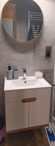 a bathroom with a white sink and a mirror at Apartamenty Jodłowa in Suwałki