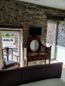 een kamer met een spiegel en een tv aan een stenen muur bij Refúgio no Douro 