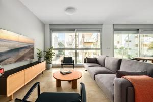 a living room with a couch and a tv at Gordon Beach Bright Spacious Stay in Tel Aviv