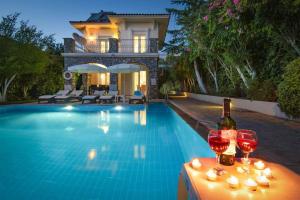 a bottle of wine and two wine glasses next to a swimming pool at Villa Tara in Ovacik
