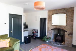 a living room with a fireplace and a green couch at THE LOFT Alnmouth in Alnmouth