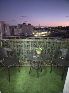 a balcony with two chairs and a table with flowers at House Mari in Catania