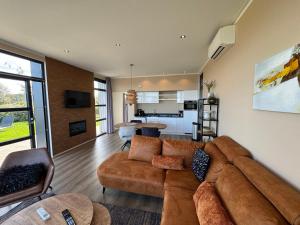 a living room with a brown couch and a kitchen at Enkhuizer Strand Chalet Strandjuwel Erste Reihe Hausnr 205 in Enkhuizen