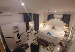 a bedroom with a large white bed and a mirror at Malaika White House Apartment & Spa in Kiwengwa