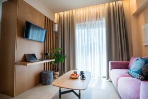 a living room with a pink couch and a table at City Core Plataia Agora in Katerini