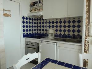 a kitchen with white cabinets and blue and white tiles at Joli studio Hardelot face mer, à 100m du centre-ville! in Hardelot-Plage +4 photos
