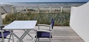 a table and chairs on a deck with the beach at Joli studio Hardelot face mer, à 100m du centre-ville! in Hardelot-Plage