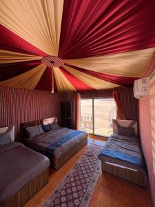 two beds in a room with a ceiling at Wadi Rum Sand moon Camp &Tour in Wadi Rum