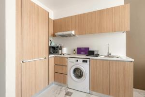 una cocina con lavadora y fregadero en Silkhaus Deluxe 1BR in Masdar City at Oasis, en Abu Dhabi Intl 9 fotos más