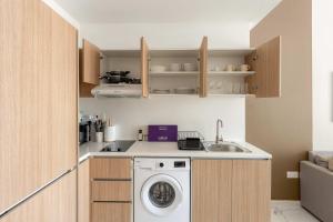 una cocina con lavadora y fregadero en Silkhaus Deluxe 1BR in Masdar City at Oasis, en Abu Dhabi Intl