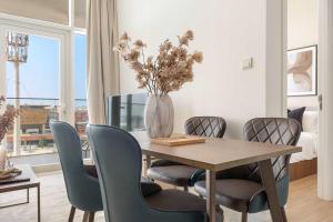Una mesa de comedor con sillas y un jarrón con flores. en Silkhaus Deluxe 1BR in Masdar City at Oasis, en Abu Dhabi Intl