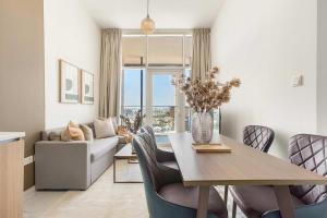Una sala de estar con una mesa y sillas y un sofá. en Silkhaus Deluxe 1BR in Masdar City at Oasis, en Abu Dhabi Intl