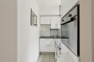 a kitchen with white cabinets and a refrigerator at BnBNova - 1BR - Les Invalides & Eiffel Tower in Paris +11 photos