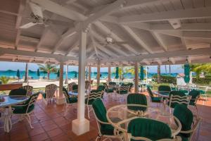 a restaurant with tables and chairs with the ocean in the background at Glitter Bay Apartment 104 in Saint James