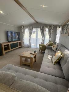 a living room with a couch and a table at Fantasy Island - Eastgate E6 - The Sierra with Hot Tub - Coastal Caravan Breaks in Ingoldmells