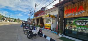 een rij motorfietsen geparkeerd voor een winkel bij Gina hostel kohlanta in Phra Ae beach +6 foto's