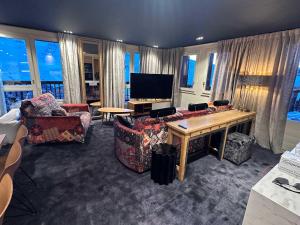 Una sala de estar con sillas, una mesa y un televisor. en Luxury Ski-In Ski-Out 4BR Apartment with 4 Baths - Val Thorens, en Val Thorens