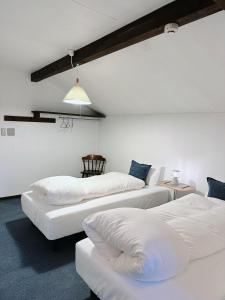 three beds in a room with white walls at Sugi Lodge in Hakuba