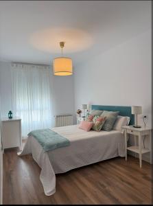 Dormitorio blanco con cama grande y lámpara en Nordés, en Vilagarcía de Arousa