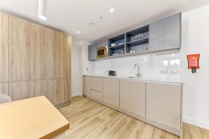 a kitchen with white cabinets and a wooden table at Brand New Ensuites In Central Leeds in Leeds +10 photos