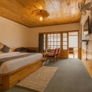 a bedroom with a bed and a wooden ceiling at Sita Hotel & Cottage, Manali - A Boutique Wellness Hotel in Manāli