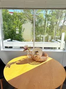une table avec un panier de fleurs et une fenêtre dans l'établissement Renovated Entire 2BR Flat, Comfort, Scenic Views, Free Parking & 10 min to Ferry, à Wellington