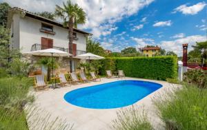 a swimming pool in a yard with chairs and umbrellas at Sablic Apartment - Opatija-Ika, in middle of olive garden with a beautiful pool in Ika