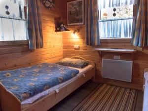 a bed in a room with wooden walls and windows at Ferienhaus Nr 5, Typ A, Feriendorf Jägerpark, Bayerischer Wald in Prackenbach