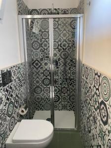 a bathroom with a toilet and a shower with tiles at La Logghia rooms in Avola +27 photos