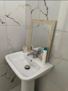 un lavabo blanc dans une salle de bain avec un miroir dans l'établissement Aura Apartaments 3, à Tirane