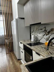 a kitchen with a counter top and a refrigerator at Prestige Ap in Ustʼ-Kamenogorsk