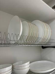 a shelf with white plates and bowls on it at Prestige Ap in Ustʼ-Kamenogorsk