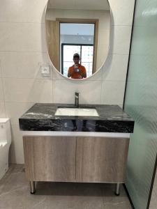 a man taking a picture of a bathroom sink with a mirror at H-Vista Suites - The Wisteria 