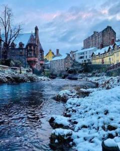 a river in a city with snow and buildings at Apart Bernard Rooms in Edinburgh