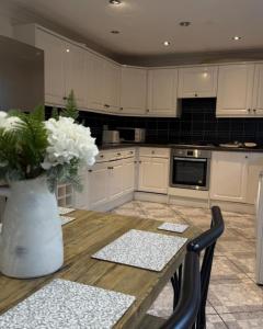 a kitchen with a wooden table with a vase of flowers at Spacious 3 Bed Apartment In Central Horsham in Roffey