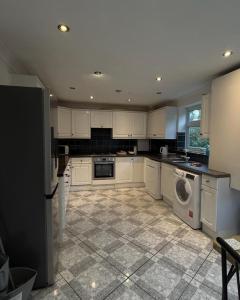 a kitchen with white cabinets and a washer and dryer at Spacious 3 Bed Apartment In Central Horsham in Roffey