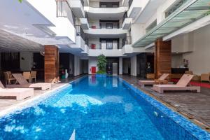 スミニャックにあるSans Vibes Hotel Seminyakのラウンジチェア付きのホテル内のスイミングプールを利用できます。