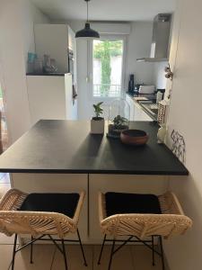 a kitchen with a black counter and two chairs at Chambre Cosy proche Part Dieu in Villeurbanne +5 photos