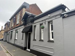 a gray building with a potted plant on a street at Sarah Hotel in Harwich +8 photos