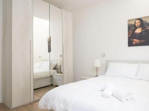 une chambre avec un grand lit blanc et un miroir dans l'établissement suite boutique viale assunta 90, à Cernusco sul Naviglio