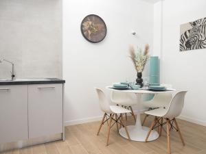 une cuisine avec une table, des chaises et une horloge murale dans l'établissement suite boutique viale assunta 90, à Cernusco sul Naviglio 13 autres photos