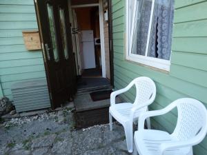 dos sillas blancas sentadas en un lado de una casa en Frendlen Metsa Apartment, en Pärnu